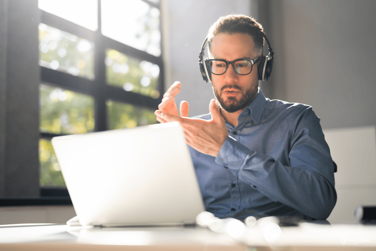 Ghostwriting Online Klausur. Mann sitzt vor dem Laptop und erklärt was.